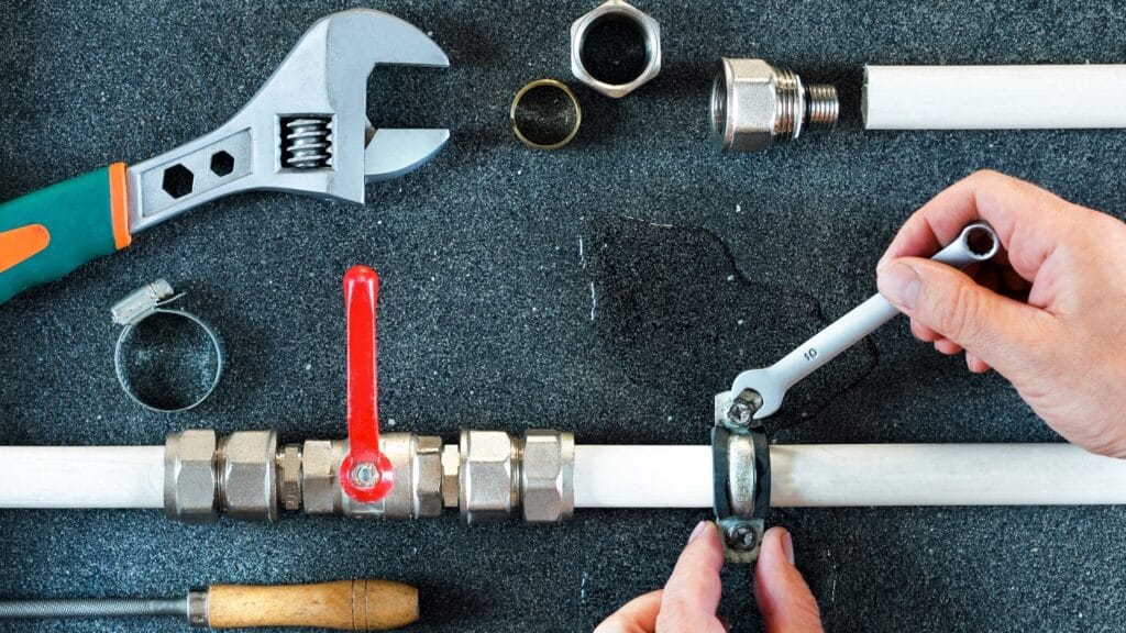 Plumber repairing a pipe valve with an adjustable wrench in Westminster