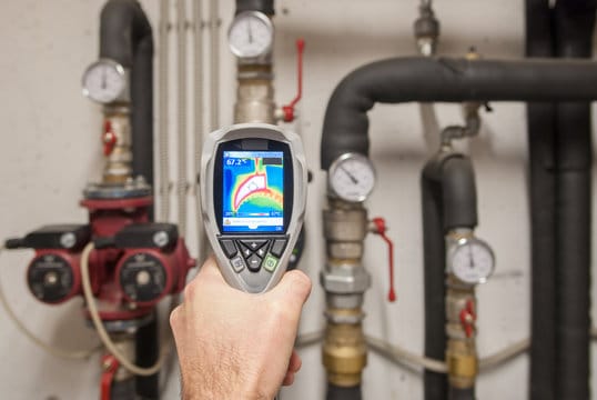 Plumber using a thermal imaging camera to inspect pipes in Westminster