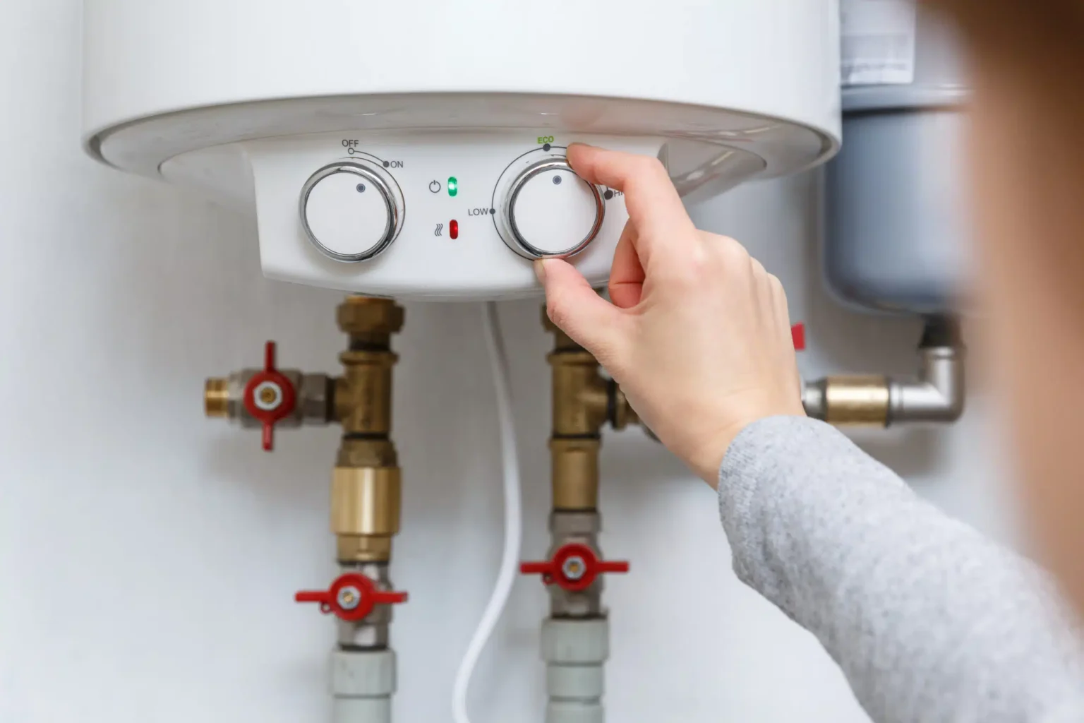 Homeowner adjusting the temperature controls on a water heater in Westminster